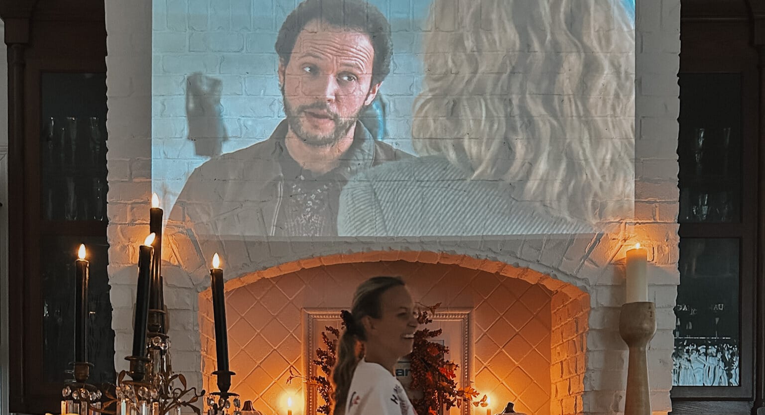 a projector in the kitchen playing when harry met sally. the kitchen is decorated for all with lots of candles.